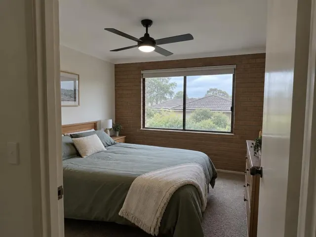 Ceiling fan with light above a bed in a brick-walled bedroom in Edgeworth