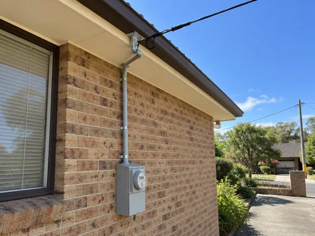 Brick house exterior with overhead service cable and meter box on the wall in Glendale